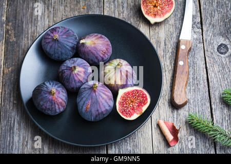 Figues fraîches sur la plaque noire sur la table en bois Banque D'Images