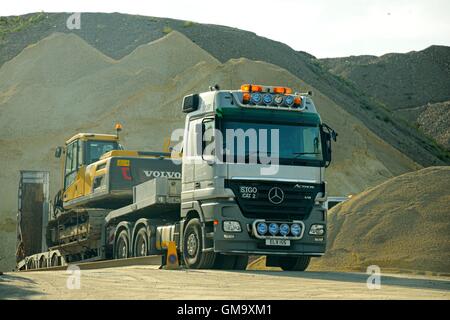 Mercedes Actros V8 avec un scanner à plat remorque transportant une Volvo Earth Mover se trouve à un site d'agrégats Banque D'Images