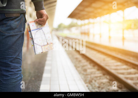 Jeune homme tenant une carte debout sur la plate-forme à la gare - travel concept Banque D'Images