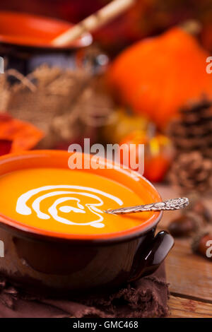Un bol de soupe au potiron crémeuse faite maison sur une table rustique avec des décorations d'automne. Banque D'Images