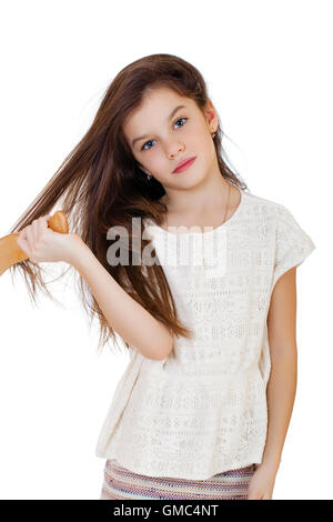 Concept de soins capillaires avec portrait de petite fille brune brosser ses longs cheveux emmêlés, indisciplinés isolated on white Banque D'Images