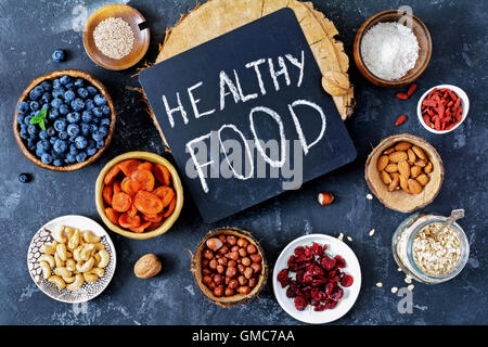 Super le choix des aliments. Divers super-aliments et aliments sains dans des bols et pots sur fond d'ardoise noire, vue du dessus. Image tonique Banque D'Images