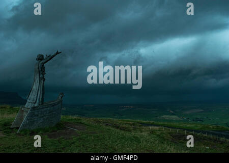 Limavady, le comté de Londonderry, Royaume-Uni, 25/08/2016 La statue de Mananna Mac Lir, un dieu de la mer Celtique, se dresse l'oeil sur la montagne Binevenagh qu'une cellule orageuse se déplace jusqu'à Lough Foyle et le long de la côte nord, ce qui porte le tonnerre, les éclairs et la pluie torrentielle avec Crédit : Eoin McConnell/Alamy Live News Banque D'Images