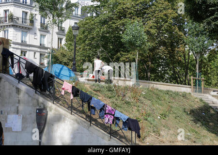 Paris, France. 26 août 2016. Les réfugiés sécher leurs vêtements lavés sur une balustrade. Les femmes lavent leurs vêtements à côté. Des centaines de réfugiés sont à la rue dans les rues autour du métro Stalingrad à Paris. Ils sont toujours dans le thread d'être déplacé par la police française, comme cela se produit sur une base régulière. Certains attendent que leur demande d'asile en cours d'approbation, d'autres sont en route vers le camp à Calais. Crédit : Michael Debets/Alamy Live News Banque D'Images