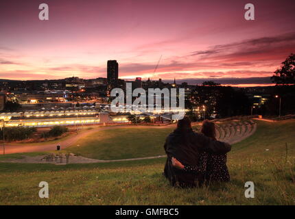 Sheffield, Yorkshire, UK. Août 26, 2016. Un couple regarder un magnifique coucher de soleil à partir de la fraise d'une colline donnant sur la ville de Sheffield au début d'août week-end férié. La récente vague de chaleur est définie sur cool avec cloud et gratuites déménagement dans au cours des prochains jours. Credit : Matthew Taylor/Alamy Live News Banque D'Images