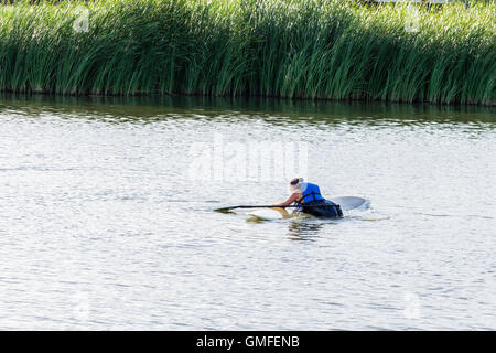 Une femme de race blanche dans son 30s'efforce de revenir sur son paddle board après tomber dans une rivière. New York, USA. Banque D'Images
