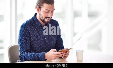 L'homme à la mode occupé à chercher son téléphone alors que l'écran sms Banque D'Images