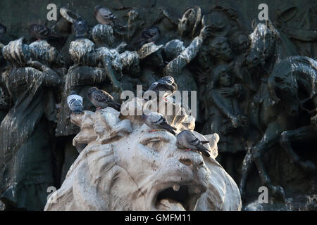 Les pigeons s'assemblant la tête de lion sur le sous-sol du Monument dédié au roi Victor Emmanuel II d'Italie conçu par le sculpteur Ercole Rosa sur la Piazza del Duomo à Milan, Lombardie, Italie. Banque D'Images