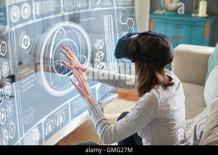 Femme assise sur le canapé à la maison le Port de casque de réalité virtuelle Banque D'Images