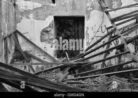 Toit effondré en copeaux des murs intérieurs et la fenêtre d'une maison abandonnée. Noir et blanc. Banque D'Images