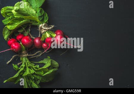 Bouquet de radis avec les feuilles sur fond noir Banque D'Images