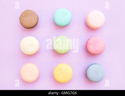 Biscuits macaron français colorés sucré sur fond lilas pastel Banque D'Images