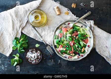 Salade de printemps avec la mâche, pamplemousse, grenat, les noix et l'huile d'olive dans la plaque de métal vintage Banque D'Images