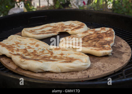 Naan Maison pain cuit à l'extérieur sur une pierre à pizza sur un barbecue au charbon de bois Banque D'Images