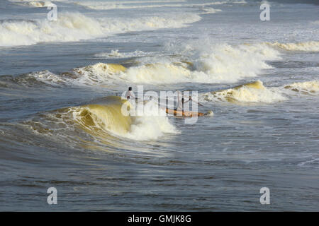 Les pêcheurs indiens entre d'énormes raz de marée. Vu à Valiyathura dans l'état du Kerala, Inde du Sud. Banque D'Images
