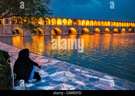 Femme iranienne en regardant le Allāhverdi hijab Khan populairement connu sous le nom de pont Si-O-seh pol "Le pont de trente-trois travées", l'un des 11 ponts d'Isfahan, Iran et le plus long pont sur la rivière Zayandeh avec la longueur totale de 297,76 mètres (976,9 pieds). Il est hautement classé comme étant l'un des exemples les plus célèbres de la conception de ponts safavides. Banque D'Images