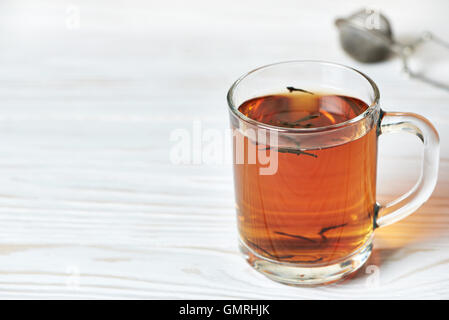 Tasse de thé et le thé-crépine sur fond de bois Banque D'Images