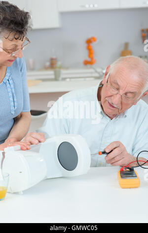 Un homme âgé à l'essai avec un multimètre, cafetière Banque D'Images