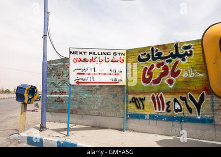 Panneau routier de dire qu'il est loin de la prochaine station d'essence sur l'autoroute dans la province d'Ispahan. La charité pour la boîte de fondation de secours Imam Khomeini, IKRF. Banque D'Images