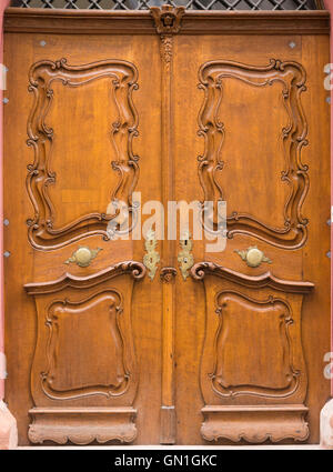 Porte en bois magnifiquement sculpté avec poignées de porte en métal décorées et boutonnières. Banque D'Images