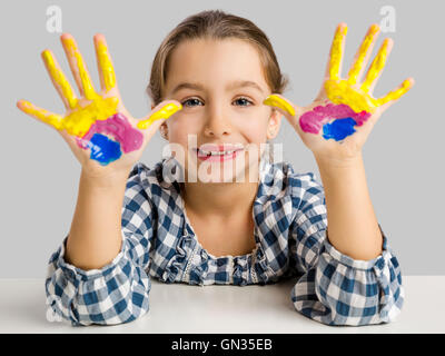 Cute smiling little girl avec les mains dans la peinture Banque D'Images