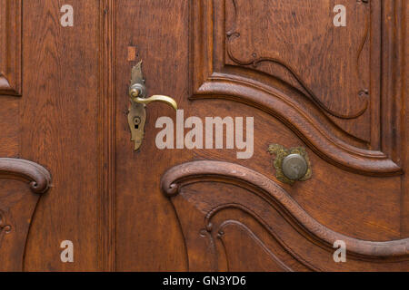 Une porte en bois rouge et marron avec une poignée de porte et bouton de porte et de sculptures en bois. Banque D'Images