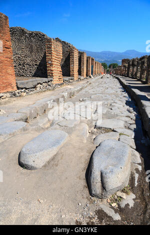 Des pierres à pas traversent une rue pavée étroite à Pompéi romaine, en Italie Banque D'Images