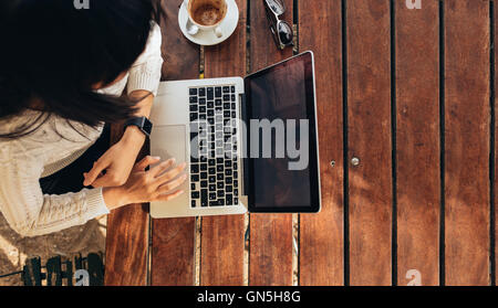 Vue de dessus de jeune femme travaillant sur son ordinateur portable dans un café. Vue d'en haut photo de femme assise à une table avec une tasse de café br Banque D'Images