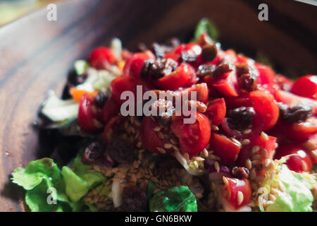 Salade d'été avec des tomates et les graines dans un bol en bois sultana Banque D'Images
