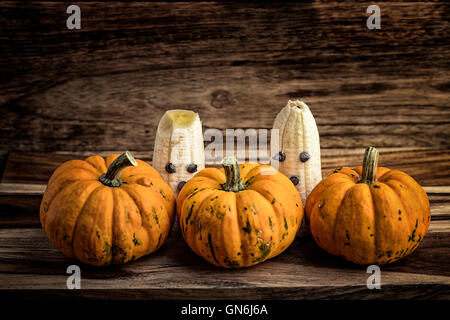 Trois citrouilles et fantômes faits avec banane et chocolat pour l'halloween sur du bois Banque D'Images