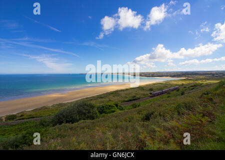 Un train passe sur la pittoresque baie de St Ives ligne de chemin de fer passant par Lelant Beach dans l'arrière-plan, en route vers St Ives. Banque D'Images