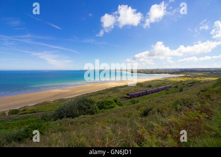 Un train passe sur la pittoresque baie de St Ives ligne de chemin de fer passant par Lelant Beach dans l'arrière-plan, en route vers St Ives. Banque D'Images