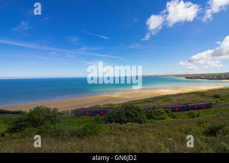 Un train passe sur la pittoresque baie de St Ives ligne de chemin de fer passant par Lelant Beach dans l'arrière-plan, en route vers St Ives. Banque D'Images