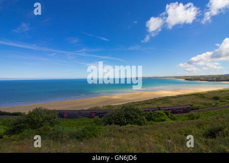 Un train passe sur la pittoresque baie de St Ives ligne de chemin de fer passant par Lelant Beach dans l'arrière-plan, en route vers St Ives. Banque D'Images