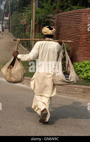 Un charmeur de serpent serpents portant son sac en tissu pris en charge avec un pôle comme il dirige pour le Taj Mahal à proximité où il y a Banque D'Images