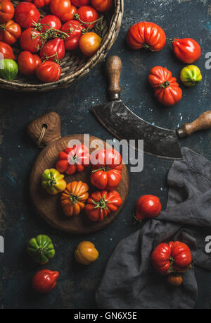 Les tomates fraîches mûres colorés heirloom dans panier et planche de bois Banque D'Images