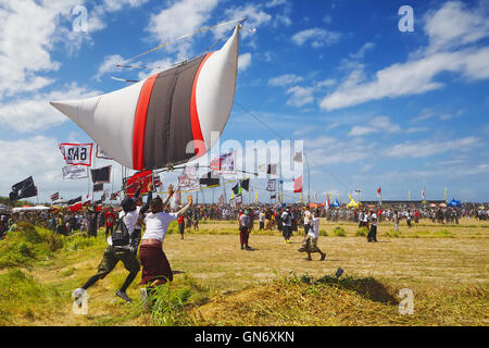 Sanur, Bali, Indonésie - 15 juillet 2012 : Groupe de joyeux garçons lancer avec plaisir très grand rouge blanc noir couleurs kite Banque D'Images