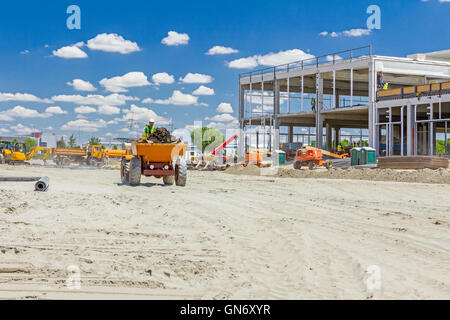 Peu de construction est à l'opérateur de la benne chantier. Banque D'Images