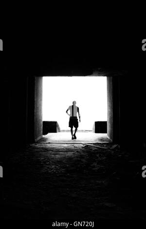 Une silhouette en noir et blanc d'un homme sur la fin d'un tunnel dans un hôtel abandonné à São Miguel, Açores. Banque D'Images