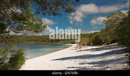 Les touristes avec Mackenzie lac allongé sur une plage de sable blanc bordée d'eau turquoise par de forêts sous ciel bleu sur l'île Fraser Banque D'Images