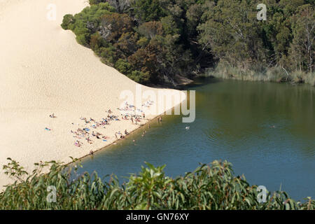 Foule de touristes de détente sur le sable de percuteur sandblow et la natation dans les eaux sombres du lac Wabby sur Fraser Island Australie Banque D'Images