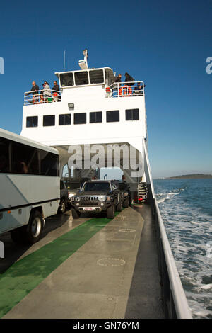 Les véhicules stationnés sur le ferry avec des passagers debout sur pont supérieur sur traversée de l'océan bleu à Fraser Island Australie Banque D'Images