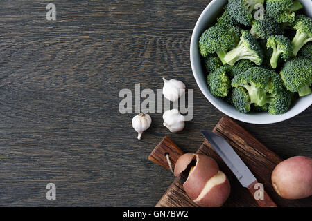 Un bol avec du brocoli, de gousses d'ail et les pommes sur fond de bois sombre. Soupe de brocoli ingrédients. Banque D'Images