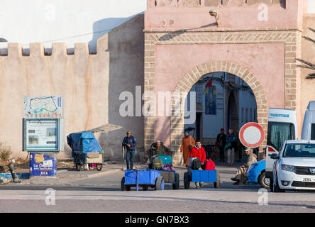 Essaouira, Maroc. Bab Marrakech. Porteurs avec leurs chariots porter les bagages des touristes en attente de leur bus. Banque D'Images