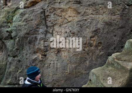 Un garçon regarde les graffiti sculptés par des soldats soviétiques en 1945 et 1968 dans les rochers de grès dans la forêt à l'extérieur du village d'Zelizy en Bohême centrale, en République tchèque. Inscriptions russe autour du pentagramme signifie : URSS 1945 et M. Yura (nom masculin) 1968 Russe. De toute évidence, les graffitis ont été sculptés par des soldats de l'Armée rouge dans les derniers jours de la Seconde Guerre mondiale en 1945, puis par les soldats de l'armée soviétique après l'invasion soviétique de 1968 en Tchécoslovaquie. Les graffiti sont situé à côté du complexe de sculptures le Harfenice (harpiste) créé par le sculpteur tchèque Vaclav Levy dans les années 1840. Banque D'Images