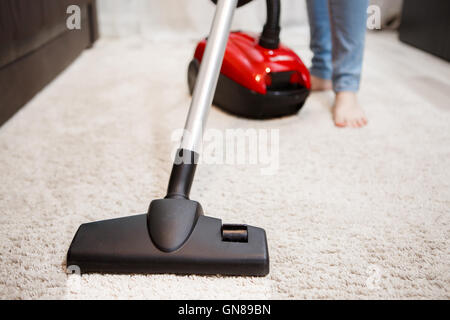 Femme dans la chambre de nettoyage, l'aspirateur tapis blanc. Image de pied femelle, rouge et noir aspirateur aspirateur de tête libre Banque D'Images