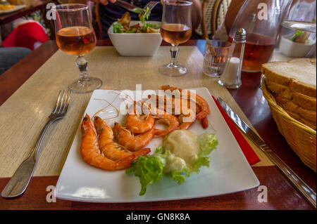 Grosses crevettes fraîches cuites et un verre de vin dans un restaurant français à Saint-Malo, Bretagne, France Banque D'Images