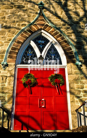 Gros plan de la porte de l'église de couleur rouge avec décoration de couronne de Noël à Hightstown, New Jersey, États-Unis, image de Noël vintage paroissial extérieur Banque D'Images