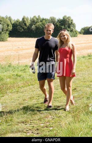 Couple en campagne du Hampshire England UK - un jeune couple en train de marcher sur les terres agricoles dans la campagne anglaise Banque D'Images