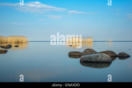 De gros rochers et le ciel bleu se reflète dans le lac Ladoga soir Banque D'Images